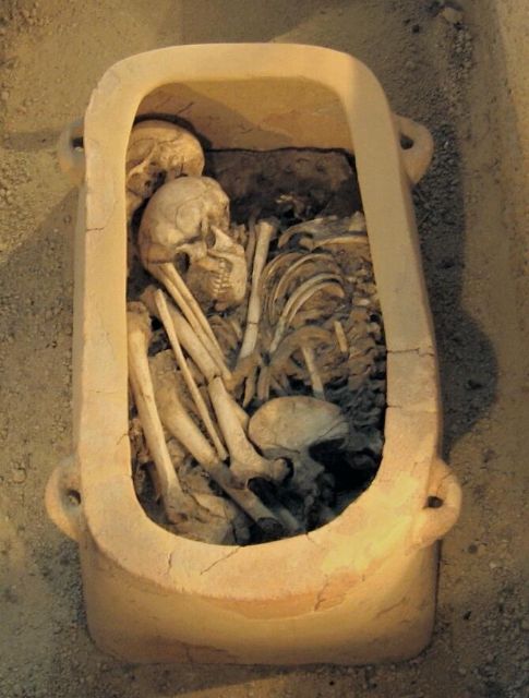 The inside of a larnax with two skeletons in fetal position - Archanes Archaeological Museum - via [Wikimedia](https://commons.wikimedia.org/wiki/File:Minoan_funeral,_AM_Archanes,_IMG_1318.jpg)