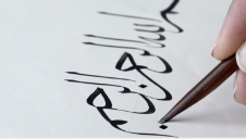 Fig 14:  The calligrapher and artist, Soraya Syed, demonstrates writing the basmala using a reed pen - [still from Islamic Calligraphy: The Development of the Art Through the Practice of its Masters with Soraya Syed](https://youtu.be/wqLfAMJIPAE)