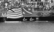 De W2x van Irene Eijs en Eeke van Nes op de Olympische Spelen wordt aangemoedigd door supporters met de vlaggen van Laga (links) en Njord (rechts) op de achtergrond.