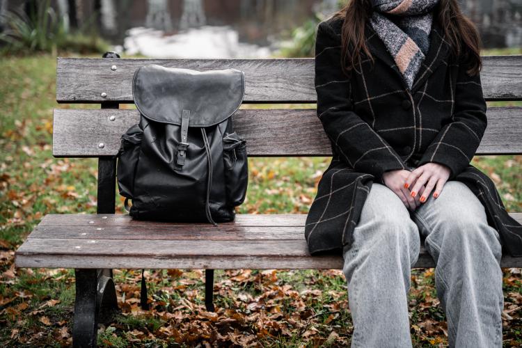 Fig. 1 A woman with her backpack beside her on a bench.