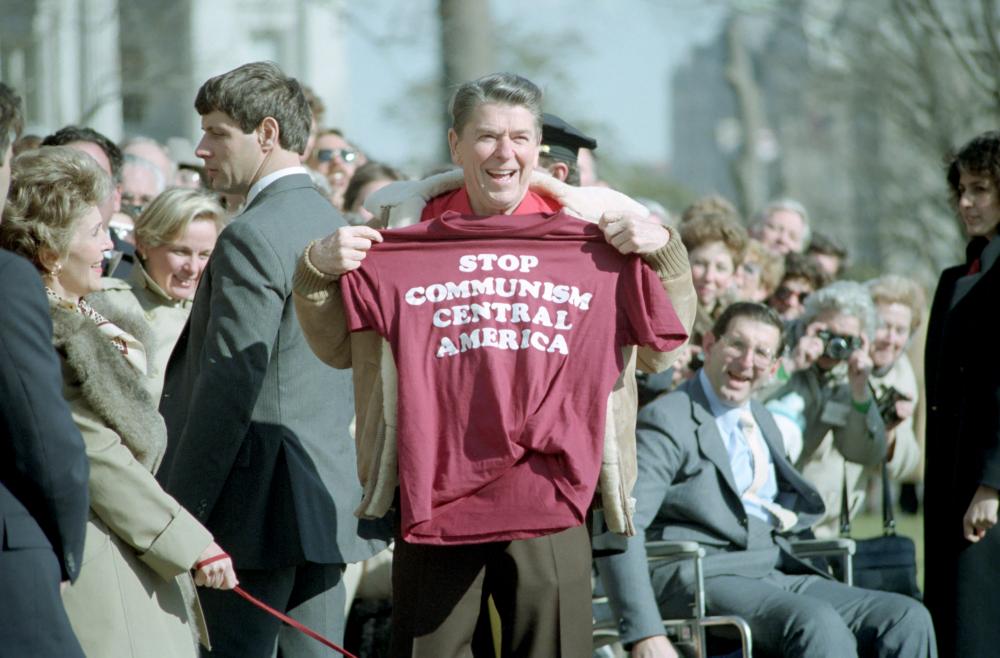 Fig. U.S. President Ronald Reagan, 7th March 1986 - [Wikimedia](https://upload.wikimedia.org/wikipedia/commons/d/d7/President_Ronald_Reagan_holding_a_Stop_Communism_T-Shirt.jpg)