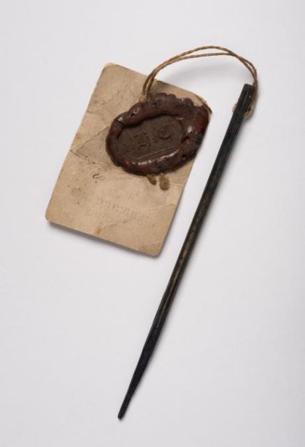 Fig. 1. The small stick is tagged with a label over half its size, bearing the Felix Driessen’s company seal. Look closer at its tip and you will see the indigo dye remains from when it was used to add detail to the material - Photography Cees de Jonge