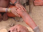 Himba girl applying otjize -[Dr. Sanusi Umar, MD](https://ugro.com/red-ochre-as-a-skin-and-hair-sunblock-an-old-himba-discovery/)