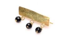Golden pin with black _ogri ai_ beads. Also used to shield young children from the evil eye, but more expensive than a bracelet or anklet - [mixed-babies](https://mixed-babies.com/contents/images/gouden-speld.jpg)